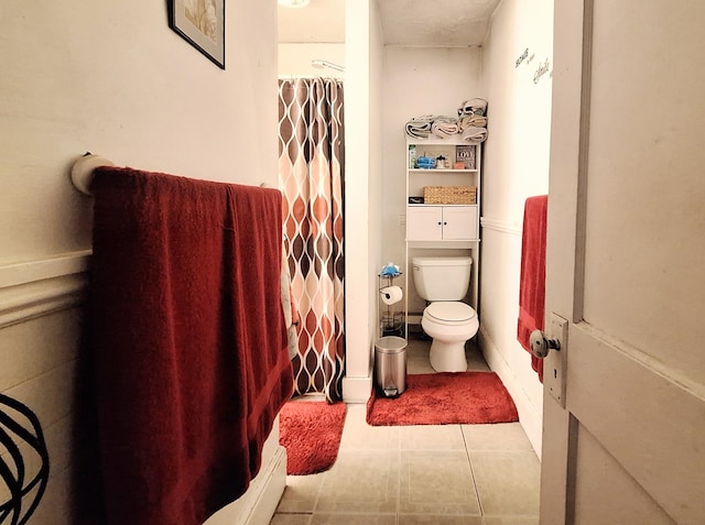 bathroom featuring a shower with shower curtain, tile patterned flooring, and toilet