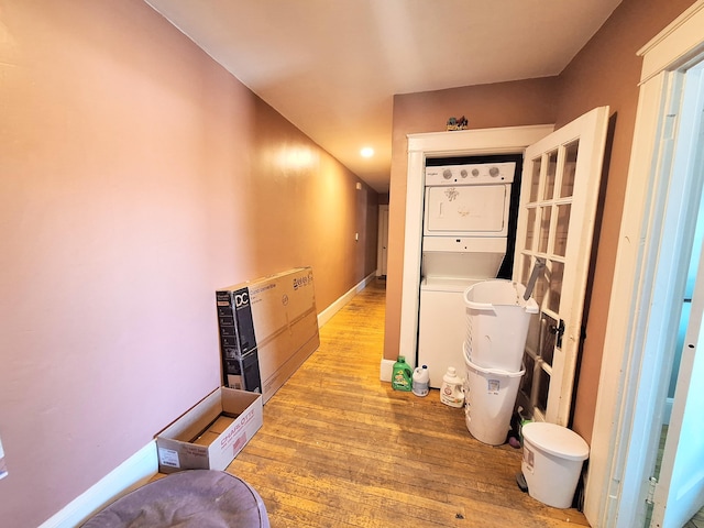 hall featuring stacked washer and dryer, baseboards, and hardwood / wood-style flooring