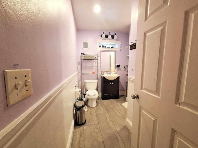 bathroom featuring a wainscoted wall, vanity, toilet, and wood tiled floor