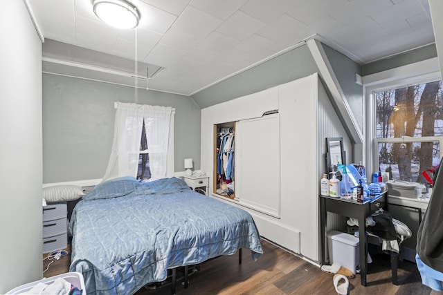 bedroom with attic access, a closet, dark wood-type flooring, and vaulted ceiling