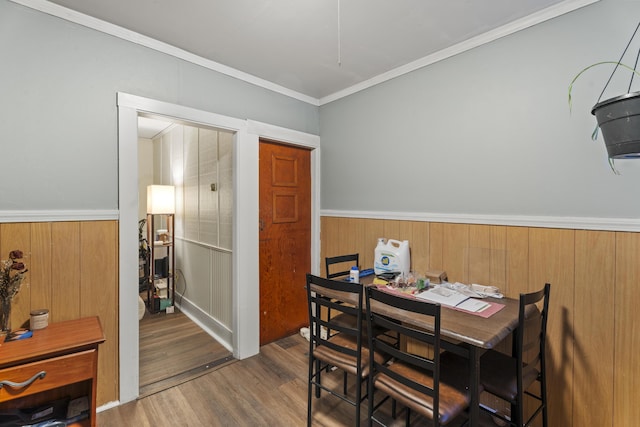 dining room featuring dark wood-type flooring, wainscoting, and crown molding