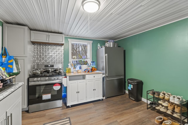 kitchen with baseboards, stainless steel appliances, light countertops, light wood-style floors, and white cabinetry