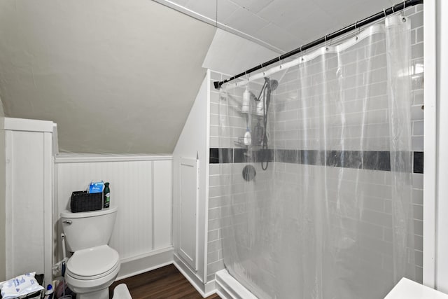 full bathroom featuring curtained shower, vaulted ceiling, toilet, and wood finished floors