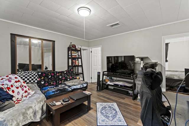 living area featuring crown molding, visible vents, and wood finished floors