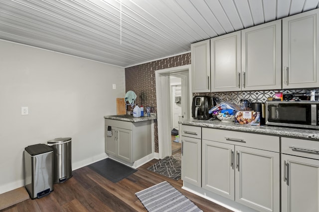 kitchen featuring baseboards, dark wood-style floors, stainless steel microwave, light countertops, and white cabinetry