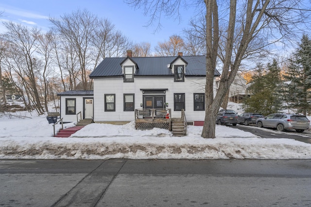 view of front of home with entry steps, metal roof, and a chimney