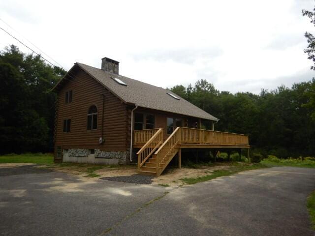 view of front of home with stairs, log exterior, a chimney, and a wooden deck