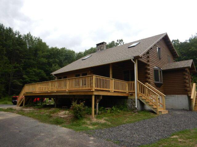 exterior space featuring a deck, a chimney, log siding, and stairs