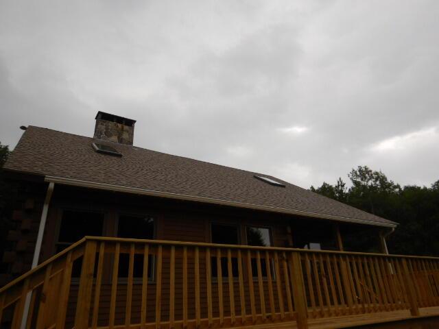 back of house with a deck, roof with shingles, and a chimney