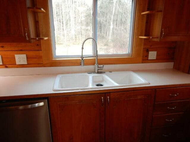 kitchen with light countertops, dishwasher, and a sink