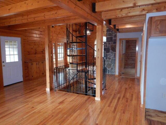 unfurnished dining area with vaulted ceiling with beams, wood walls, wood ceiling, and light wood-style floors