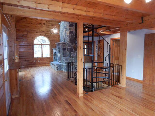 unfurnished room with vaulted ceiling with beams, wooden walls, stairway, and wood finished floors