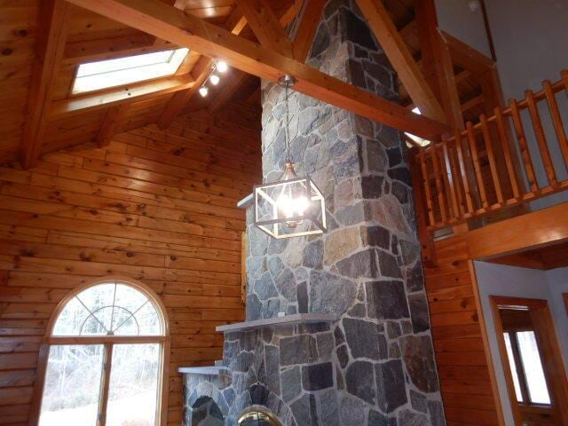 unfurnished living room with high vaulted ceiling, a skylight, and beam ceiling