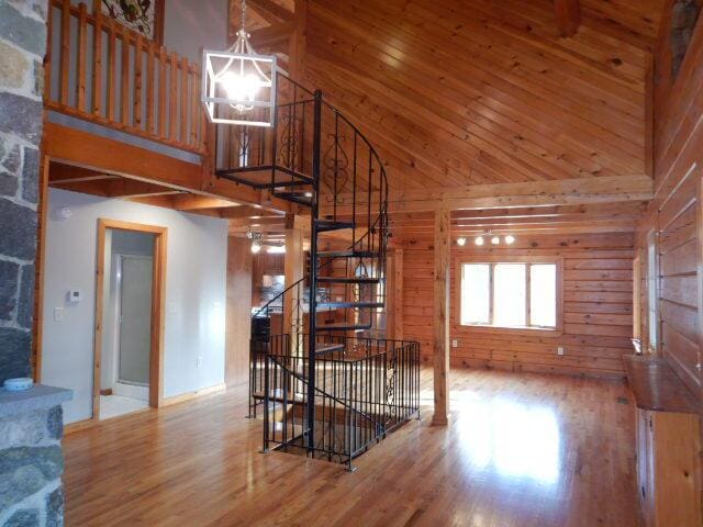 living area with a high ceiling, wood finished floors, and wooden walls