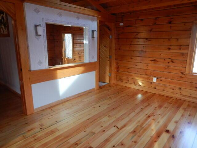 empty room with wooden walls and light wood-style flooring