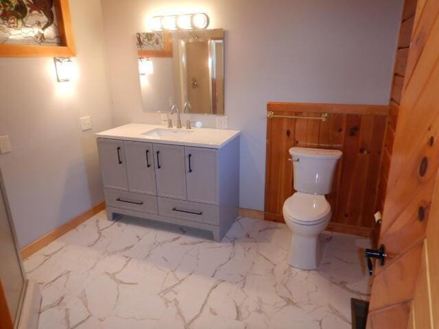 bathroom with toilet, marble finish floor, baseboards, and vanity