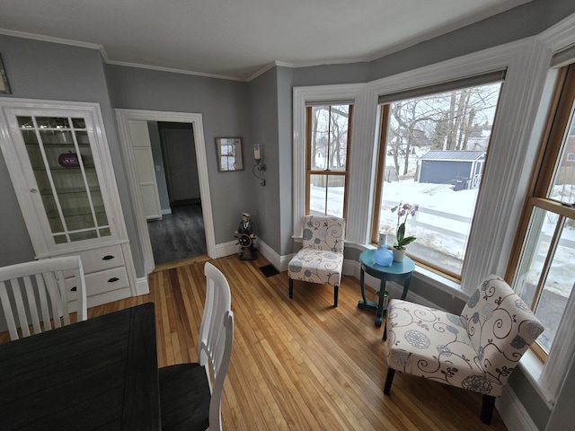 living area featuring light wood-style floors, crown molding, and baseboards