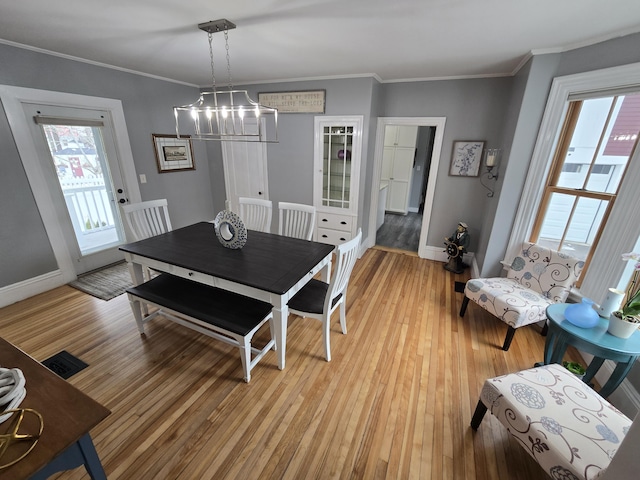 dining room featuring light wood-style flooring, baseboards, and crown molding