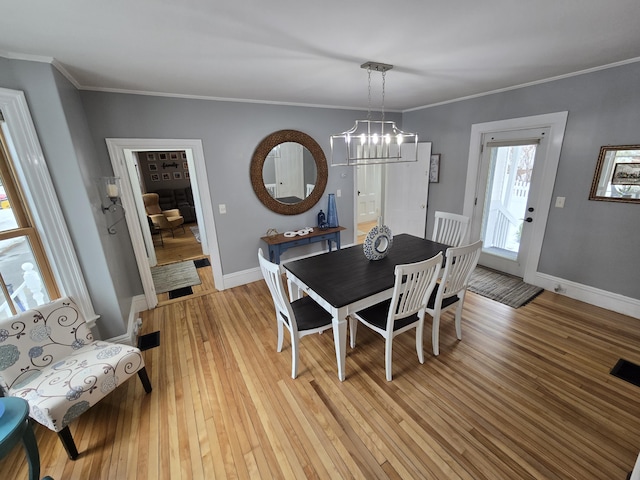 dining area with ornamental molding, light wood-type flooring, and baseboards