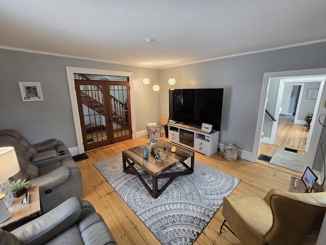 living room with baseboards, crown molding, stairway, and light wood finished floors