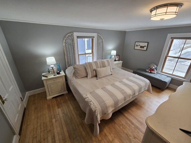 bedroom featuring ornamental molding, wood-type flooring, and baseboards