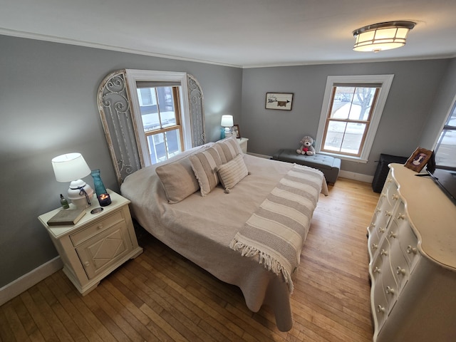 bedroom with light wood-style flooring, ornamental molding, and baseboards