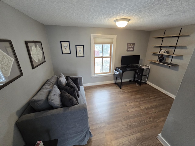 living room with a textured ceiling, baseboards, and wood finished floors