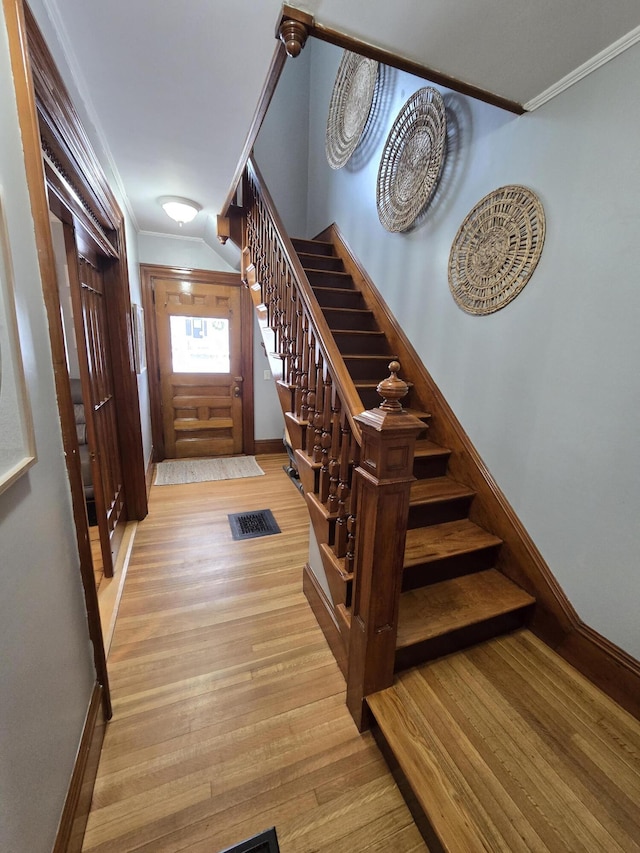 entryway featuring light wood-style flooring, visible vents, baseboards, ornamental molding, and stairway