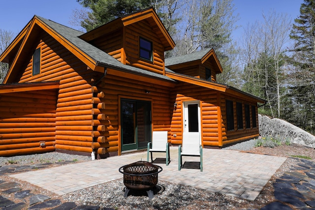 51 Short Point Way, Orland, ME 04472 - rear view of property featuring a fire pit, a patio, roof with shingles, and log exterior