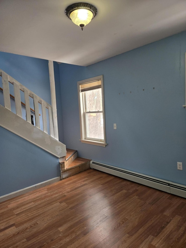 empty room featuring a baseboard heating unit and wood finished floors