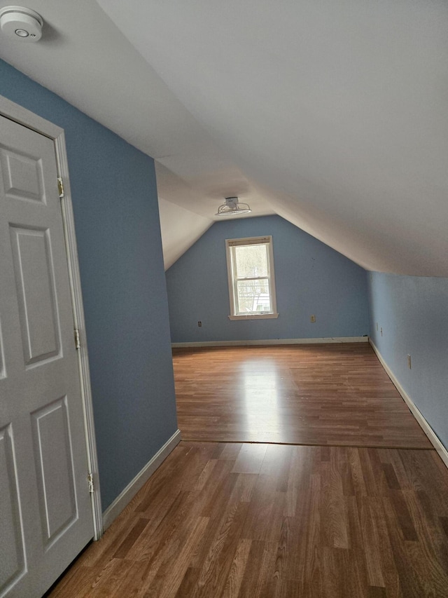 additional living space with lofted ceiling, baseboards, and wood finished floors