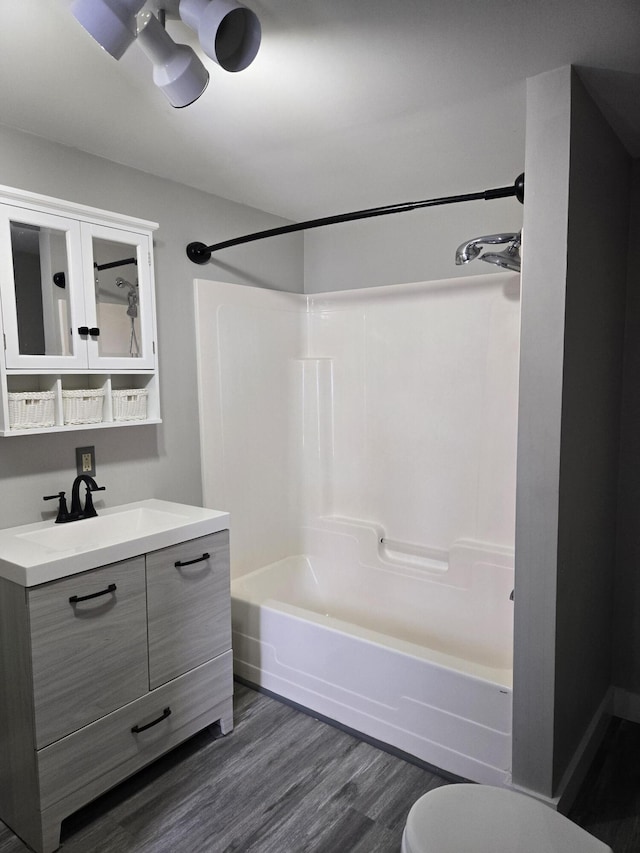 full bathroom with washtub / shower combination, vanity, toilet, and wood finished floors