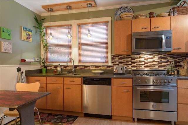 kitchen with dark countertops, ornamental molding, stainless steel appliances, and a sink