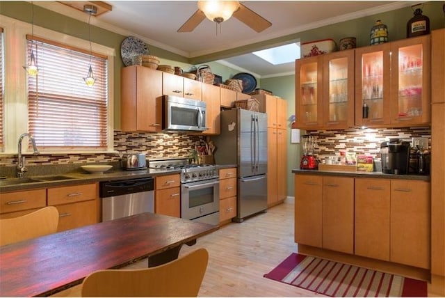 kitchen with a sink, ornamental molding, stainless steel appliances, dark countertops, and tasteful backsplash