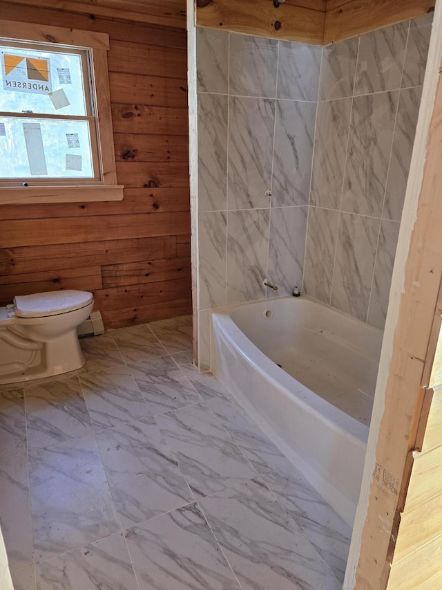 full bathroom with a bathtub, marble finish floor, wood walls, and toilet