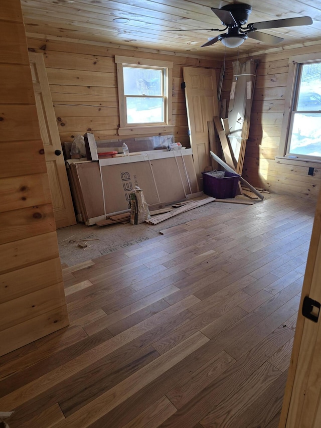 unfurnished room featuring a ceiling fan, wooden walls, and light wood finished floors