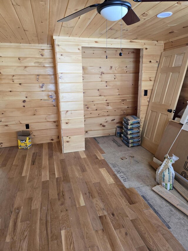 additional living space with wooden ceiling, wooden walls, and wood finished floors