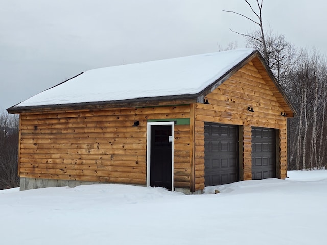 snow covered garage featuring a detached garage