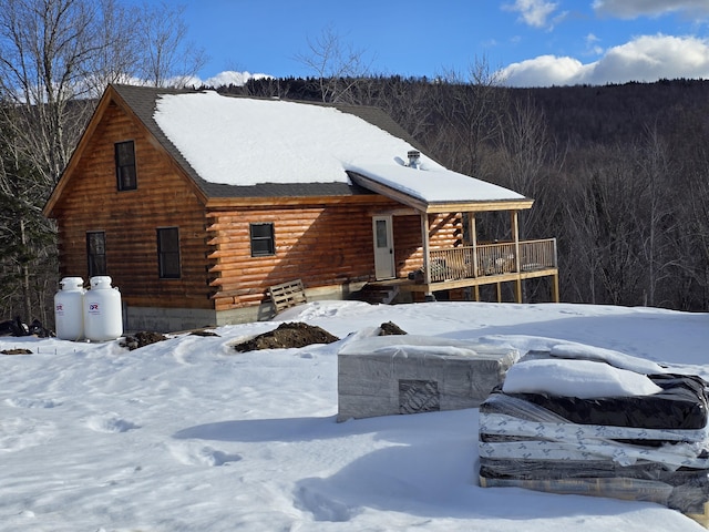 log home with a forest view, a porch, and log siding