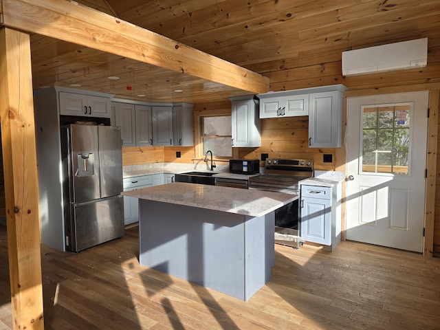 kitchen featuring stainless steel appliances, a sink, beam ceiling, hardwood / wood-style floors, and a wall mounted air conditioner