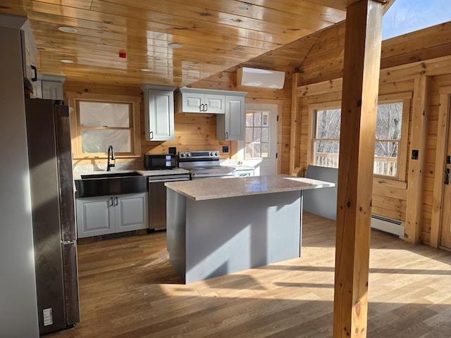 kitchen with appliances with stainless steel finishes, wood ceiling, a sink, and wooden walls