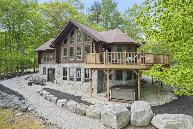 rear view of house featuring a patio, a hot tub, a deck, log siding, and stone siding