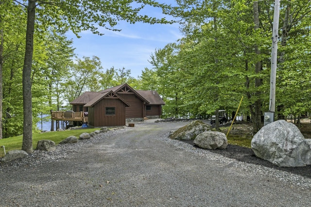 exterior space with board and batten siding, gravel driveway, and a deck with water view