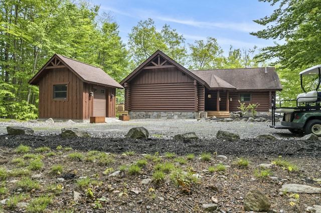 log cabin with a garage, an outdoor structure, log exterior, and board and batten siding