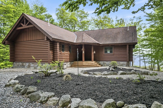 log-style house featuring a shingled roof and log siding