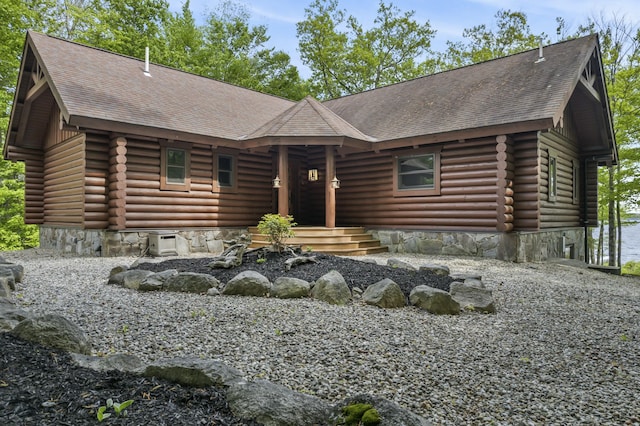 log-style house featuring log exterior and roof with shingles