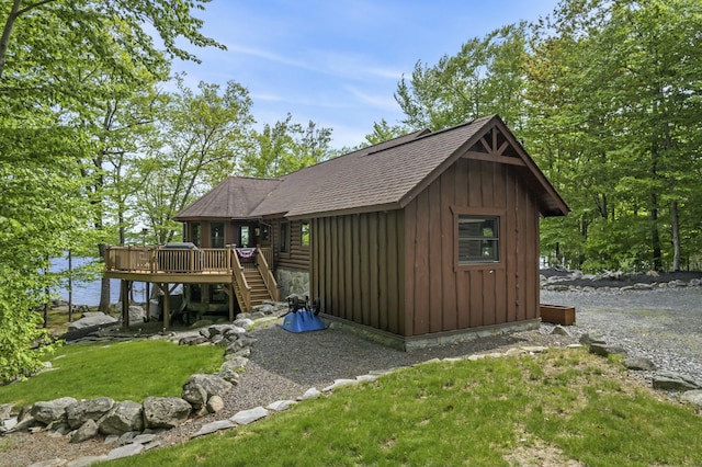 exterior space featuring a deck, a shingled roof, board and batten siding, and stairway