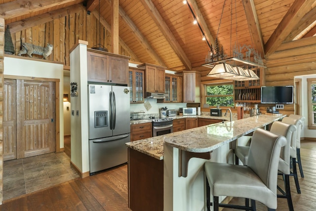 kitchen with stainless steel appliances, brown cabinetry, dark wood-type flooring, wooden ceiling, and under cabinet range hood