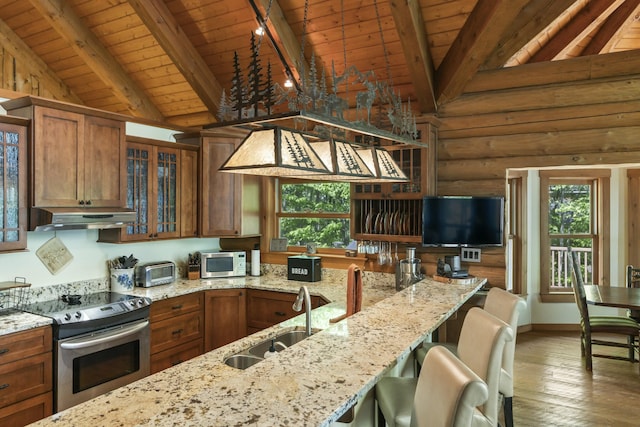 kitchen featuring brown cabinets, lofted ceiling with beams, appliances with stainless steel finishes, a sink, and under cabinet range hood