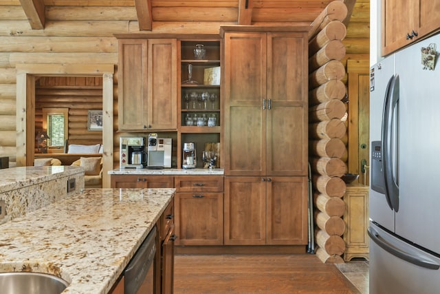 kitchen with appliances with stainless steel finishes, light stone counters, wood finished floors, and beamed ceiling